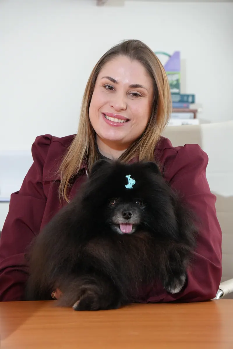 Dra. Polyana Pivovar, médica-veterinária e responsável técnica da Emporium Pet, com um spitz preto no colo
